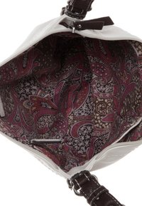 Borsa bianca con un esterno texturizzato e tracolla marrone. L'interno presenta un motivo paisley in bordeaux e crema su uno sfondo scuro.