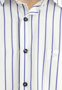 Camicia bianca con bottoni, caratterizzata da righe verticali viola, colletto corto e bottoni neri. Include una tasca sul petto con dettaglio del logo.