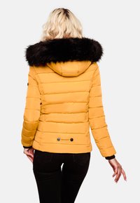 Yellow puffer jacket with a black fur-trimmed hood, quilted design, and a logo tag near the hem. Features black buttons on cuffs.