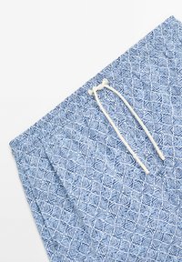 Shorts blu a fantasia realizzati in tessuto morbido, con un design geometrico. Una vita elastica con un cordoncino bianco nella parte superiore.