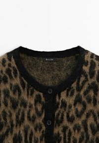Cardigan à imprimé léopard brun et noir, en tissu pelucheux, avec des bordures noires et deux boutons noirs visibles à l'avant.
