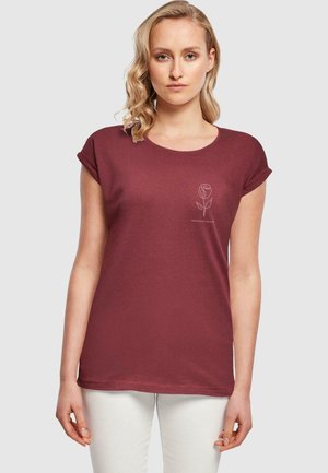 Burgundy t-shirt med korte omviklede ærmer, rund halsudskæring og en rosegrafik i hvid på venstre brystområde. Blødt bomulds materiale.