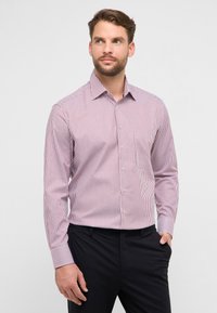 Overhemd met lange mouwen en knopen, in rood-witte verticale strepen, met een kraag en een zak, gecombineerd met donkere broek. Zachte stoftextuur.