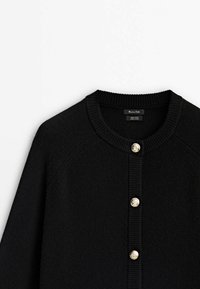 Cardigan en laine noire avec col rond côtelé et devant côtelé, présentant quatre boutons dorés embossés.