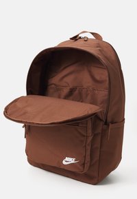 Bruine Nike rugzak met een ruime binnenkant en een voorste ritsvak. Gemaakt van duurzaam materiaal, met een handvat aan de bovenkant en verstelbare schouderbanden.