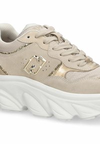 Baskets beiges avec une tige en daim, des accents dorés, des sections en mesh texturé et une semelle épaisse blanche. Comprend des lacets arrondis et un détail de logo.