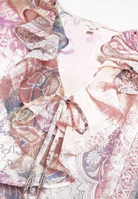 Blusa leggera a fantasia in rosa chiaro, blu e viola. Presenta dettagli arricciati e nastri di perline al collo. Tessuto testurizzato.