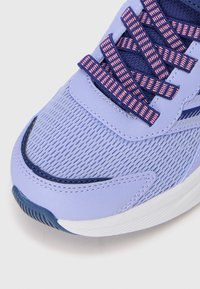 Close-up of purple and navy running shoe with pink and navy patterned laces and white cushioned sole.