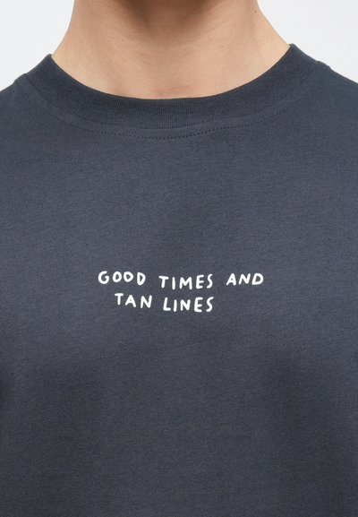 Σκούρο γκρι βαμβακερό T-shirt με στρογγυλή λαιμόκοψη και λευκή τυπωμένη φράση που λέει «ΚΑΛΕΣ ΣΤΙΓΜΕΣ ΚΑΙ ΜΑΥΡΙΣΜΕΝΑ ΣΗΜΑΔΙΑ» στο στήθος.