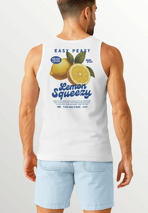 White tank top with a graphic design featuring lemon images, blue text saying "Lemon Squeezy," and leaf accents; light blue shorts visible.