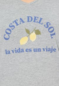 Szara bawełniana koszulka z dekoltem w serek, z niebieskim napisem "COSTA DEL SOL" nad dwoma żółtymi cytrynami i zielonymi liśćmi, oraz z napisem "la vida es un viaje" poniżej.