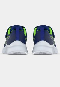 KĪPU pāris tumši zilu sporta apavu ar neona zaļo odere, baltām zālēm un aizmugurējām cilpām, redzami no papēža uz viendabīga fona.