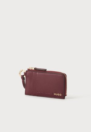 Porte-cartes en cuir bordeaux avec fermeture éclair dorée, porte-clés, plusieurs emplacements pour cartes et logo "HUGO" embossé en or à l'avant.