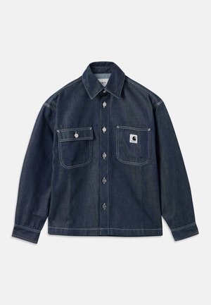 Veste en jean foncé à manches longues, deux poches poitrine, boutons argentés et coutures blanches. Comprend un écusson logo sur la poche gauche.