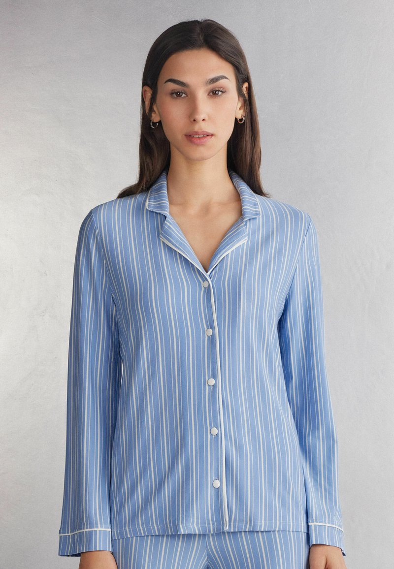 Blauwe gestreepte pyjamaspijker met lange mouwen, met een notch-kraag, knoopsluiting en witte accenten langs de randen. Glad stofoppervlak.