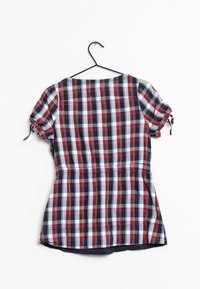 Rot, marineblau und weiß karierte Bluse mit kurzen Puffärmeln, elastischem Taillenbund und V-Ausschnitt, die an einem schwarzen Haken vor einem weißen Hintergrund hängt.