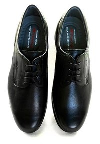 Zapatos de cuero negro con un acabado suave, punta redonda, cuatro ojales para los cordones y un sutil logo grabado en el costado. Ajuste ajustable.