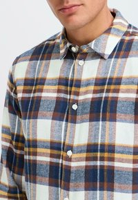 Geruite button-up shirt van lichte stof met een mix van blauw, bruin, geel en crème kleuren, voorzien van witte knopen en een klassieke kraag.