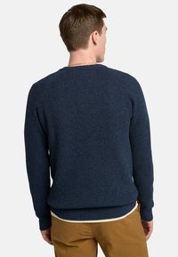 Maglione lavorato a maglia blu navy con texture a coste, colletto tondo e maniche lunghe. L'orlo è leggermente più lungo sul retro per una maggiore copertura.