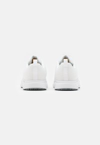 Baskets de sport blanches avec une tige en maille texturée, un col rembourré et une semelle grise contrastante. Comprend des languettes pour un enfilage facile.