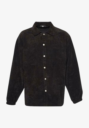 Black corduroy shirt jacket with a collar, front button closure, two chest pockets, and long sleeves. Textured fabric with subtle sheen.
