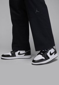 Black and white Nike Air Jordan sneakers with leather upper, perforated toe, and signature logo accents on the side and heel.