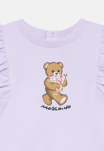 Πουλόβερ λεβάντας με ριμπ λαιμόκοψη και φουσκωτά μανίκια. Διαθέτει εκτύπωση αρκούδας που κρατά λουλούδια στο κέντρο με το κείμενο "MOSCHINO" από κάτω.