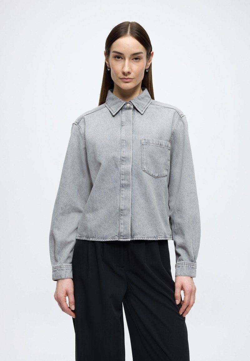 Szürke farmering galléros nyakkivágással, elülső zsebbel és hosszú ujjakkal, laza fazonnal és minimalista dizájnnal.