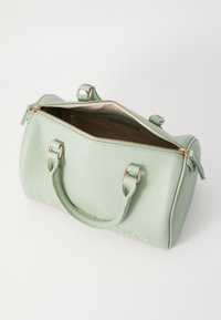 Světle zelená kožená kabelka s texturovaným povrchem, zlatými kovovými doplňky, zipovým uzávěrem a dvojitými uchy. Interiér odhaluje béžovou podšívku.