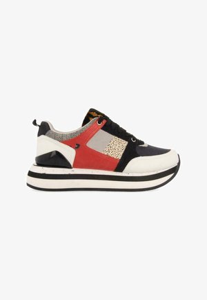 Klobiger Sneaker mit dicker, schwarz-weiß gestreifter Sohle, rot-schwarz-beigen Paneelen, Animal-Print und schwarzen Schnürsenkeln, Seitenansicht vor weißem Hintergrund.