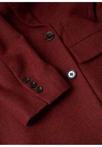 Manteau en laine bordeaux avec un revers cranté, trois boutons noirs sur le poignet, et une texture douce et élégante.