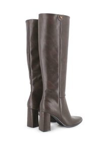 Botas de cuero marrón hasta la rodilla con punta afilada y tacones cuadrados robustos, con una textura suave y un acento de logo cerca de la parte superior.
