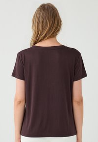 T-shirt marrone a maniche corte con collo rotondo, realizzata in materiale morbido. Design semplice con una vestibilità dritta e senza motivi o dettagli visibili.
