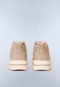 Sneaker alte in suede beige con una texture liscia, dotate di un tallone rinforzato e una suola in gomma bianca con dettagli sottili.