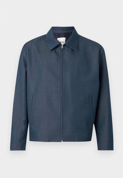 Ανδρικό σκούρο μπλε μπουφάν με φερμουάρ, μυτερό γιακά και δύο κάθετες πλευρικές τσέπες, εμφανίζεται σε απλό ανοιχτό φόντο.