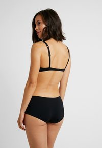 Schwarzer BH und passender Slip. Der BH hat verstellbare Träger und ein glattes, nahtloses Design, während der Slip einen tief geschnittenen Bund hat.