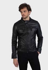 Čierna kožená bunda s vysokým golierom, predným zipsom a dvoma prednými vreckami. Úzky strih s jemnými detailmi šitia.
