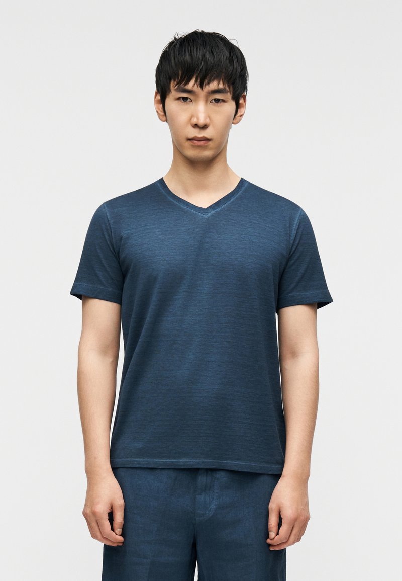 Κοντομάνικο T-shirt με V λαιμόκοψη σε σκούρο μπλε με  υφή; συνδυασμένο με παντελόνι σε σκούρο μπλε. Απλός, καθημερινός σχεδιασμός.