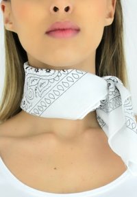 Écharpe en soie blanche avec un motif cachemire noir, nouée autour du cou. Texture lisse avec un design léger et fluide.