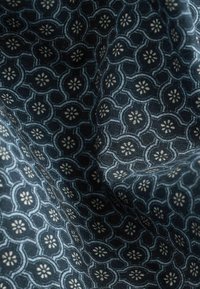 Tejido azul oscuro con un patrón floral repetitivo en blanco, con formas distintas y una textura tejida.