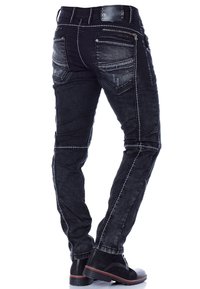 Schwarze Denim-Jeans mit schmaler Passform, ausgestattet mit weißen Nähten, Reißverschlusstaschen und strukturierten Akzenten entlang der Beine. Schwarze Stiefel sind sichtbar darunter.