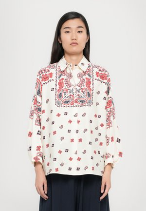 White long-sleeve blouse featuring a detailed red and blue paisley pattern, with a button-up front and relaxed fit.