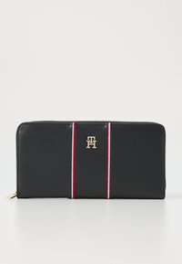Black leather wallet features red and white stripes, gold logo accent, and zip closure. Smooth texture with sleek rectangular shape.