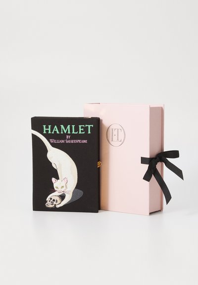 Copertina nera di un libro con un gatto bianco che gioca con un teschio, intitolato "Amleto di William Shakespeare", accanto a una scatola rosa legata con un nastro nero.