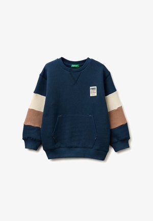 Marineblauer Pullover mit beigen und braunen Ärmelstreifen, Fronttasche und "Free Spirit"-Aufnäher auf der Brust.