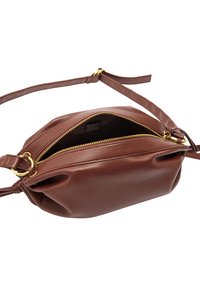 Brązowa skórzana torba na ramię z złotymi detalami zamka, miękka tekstura, zaokrąglony kształt i wąski regulowany pasek. Otwarta, aby pokazać wnętrze.