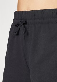 Sorte joggebukser med elastisk midje og justerbar snor. Har en glatt, myk tekstur og sidelommer.