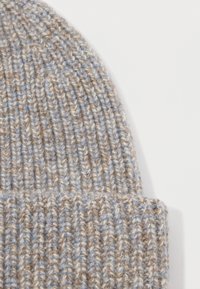 Knitted beanie in a soft blend of light blue and beige yarn. Features a ribbed texture and a snug, folded design at the bottom.