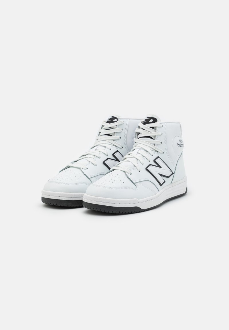 Sneaker alte bianche in pelle con accenti neri, punta perforata, lacci bianchi piatti e suola in gomma nera testurizzata.