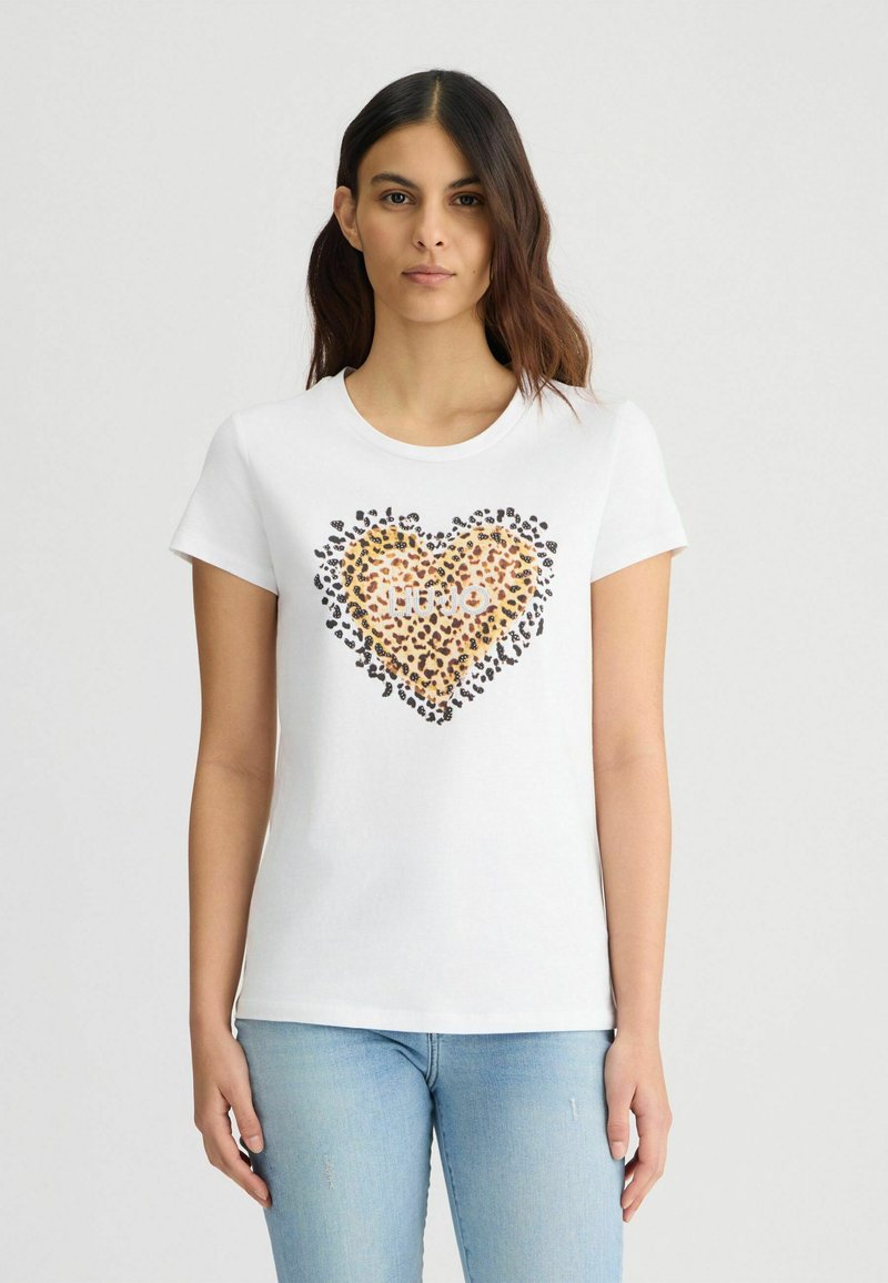 T-shirt en coton blanc avec un design en forme de cœur composé de taches de léopard et de contours noirs, col rond et manches courtes.